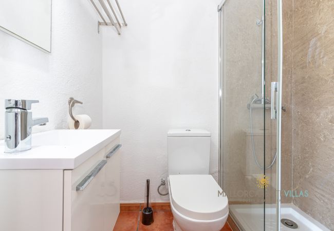 Bany modern amb dutxa, lavabo i vàter. Baño con ducha de cristal, lavabo moderno y WC en un estilo sencillo y funcional.