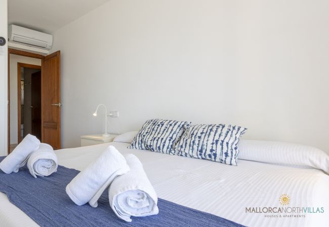 Dormitorio con cama doble y aire acondicionado en Pollensa Cama doble con cojines azules y aire acondicionado en Pollensa
