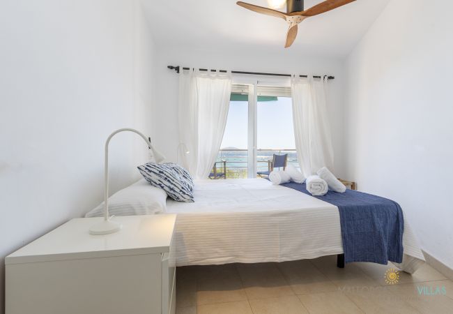 Dormitorio doble con vistas al mar en Puerto de Pollensa Dormitorio con cama doble, mesita blanca y vistas al mar