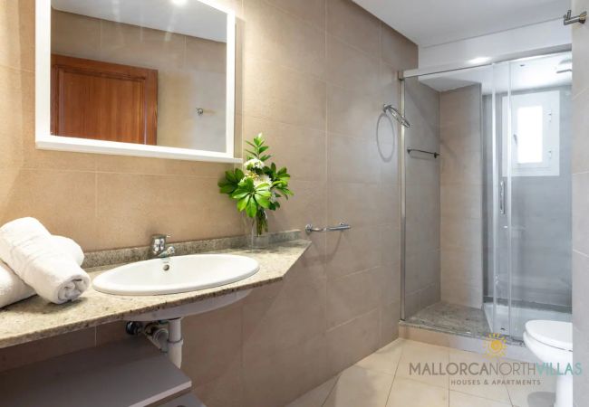 Baño moderno con ducha en Puerto de Pollensa Baño moderno con ducha de cristal, lavabo y toallas en Pollensa