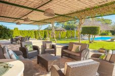 Terraza cubierta con sofás y mesas de jardín al lado de la piscina