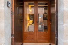 Entrada principal con portón de madera y puerta de cristal, acceso a un interior acogedor y bien iluminado.