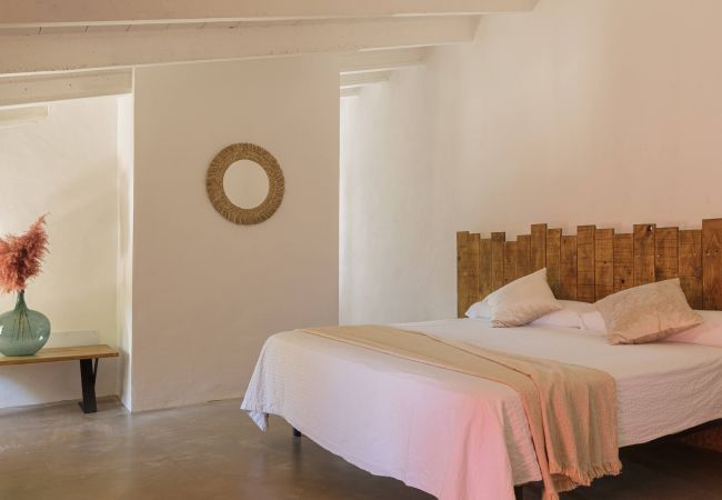 Dormitorio principal de Finca Binissati, cama doble y estilo natural Dormitorio con cama doble, cabecero de madera y luz cálida en Finca Binissati