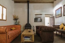 Salón con chimenea, sofás de cuero y vigas de madera en finca mallorquina.