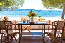 Private Terrasse mit Holzstühlen und Tisch, mit Blick auf das Meer und Boote in der Bucht.