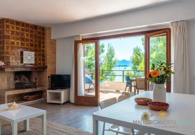 Wohnzimmer mit Kamin und Meerblick – Puerto Pollensa Wohnzimmer mit Kamin und Essbereich mit Zugang zur Terrasse und Meerblick in der Ferienwohnung Bel, Pollensa, Mallorca