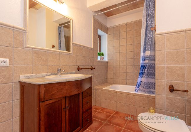 Baño completo con bañera y mueble de lavabo de madera Bathroom with bathtub, wooden sink unit, large mirror and exterior window.