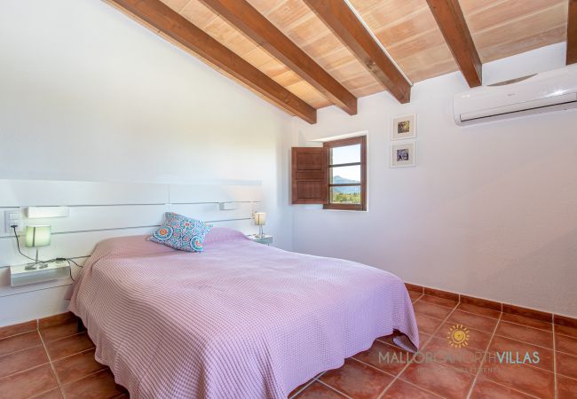 Bedroom with double bed and exposed wooden beams Bedroom with double bed, air conditioning and exposed wooden beams in bright setting.