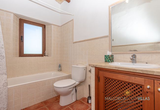 Full bathroom with bathtub and wooden vanity Bathroom with bathtub, wooden vanity, mirror and window providing natural light.