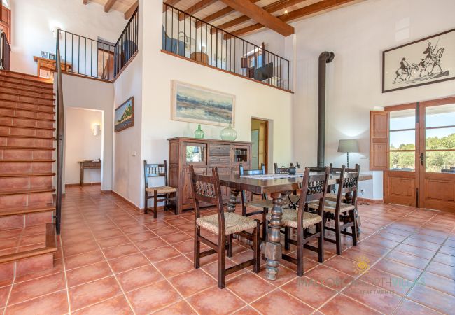 Rustic dining room with stairs and terrace access Dining room with wooden table, staircase to upper floor and terrace access in holiday finca Mallorca