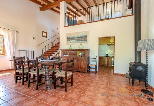 Rustic indoor dining room with wood stove in finca Indoor dining room with wooden table, wood stove and high ceilings in holiday finca Mallorca
