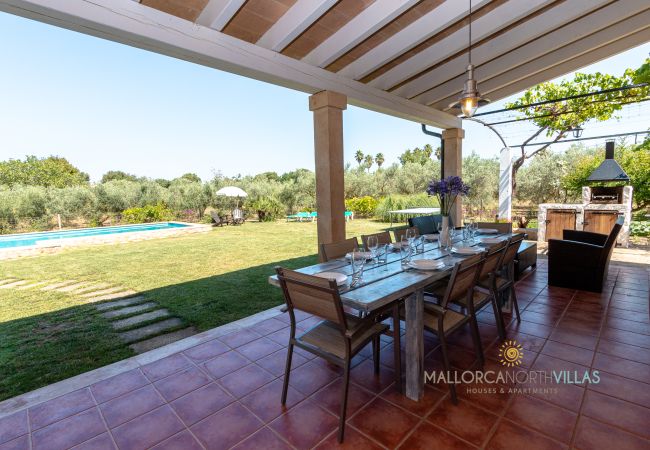 Covered terrace with outdoor dining in Mallorca finca Covered terrace with dining table and views of garden and pool in Mallorcan finca