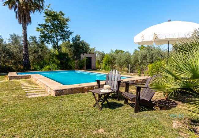 Pool with sunbeds and umbrella in the garden Private pool with wooden sunbeds and white umbrella in a spacious Mediterranean garden.