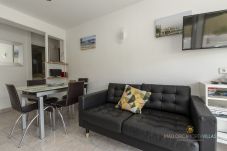 Living-dining room with sofa, dining table and TV in a bright area of the Port de Pollença apartment.