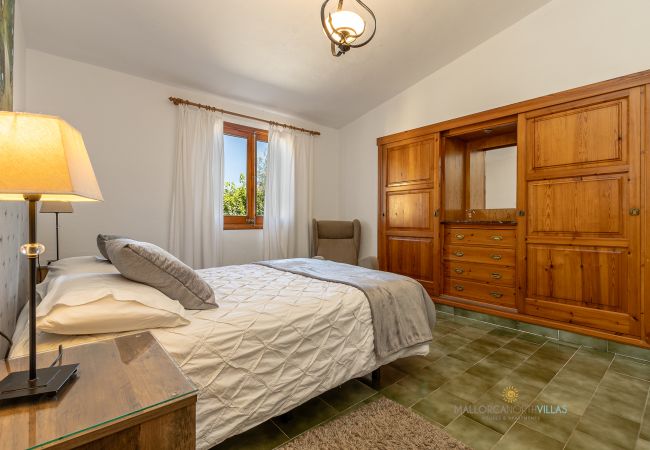 La Sort Llarga Bedroom – Double bed and wardrobe in Pollença Bedroom with double bed, wooden wardrobe and window at La Sort Llarga, Pollença
