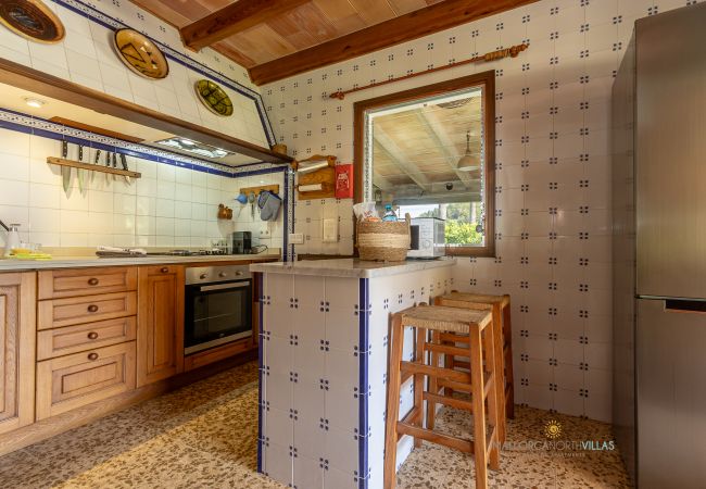 La Sort Llarga Kitchen – Wooden cabinets and bar Pollença Kitchen with breakfast bar, stools, oven and wooden cabinets at La Sort Llarga, Pollença