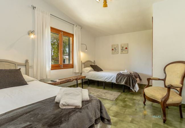 Twin bedroom with natural light at La Sort Llarga Twin beds with window and armchair in the room at Pollença