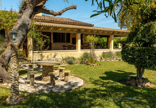La Sort Llarga Exterior – Garden and terrace in Pollença Garden with stone table and covered terrace at La Sort Llarga villa, Pollença, Mallorca