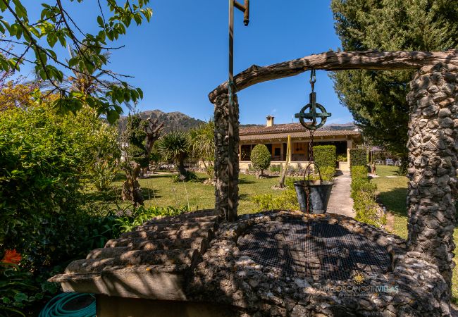 Stone well and garden at La Sort Llarga Pollença Rustic well and façade of La Sort Llarga villa, Mallorca