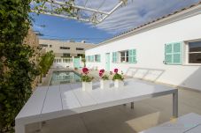 Outdoor dining area with table, private pool and Mediterranean-style façade at Villa Veles Dos in Mallorca.