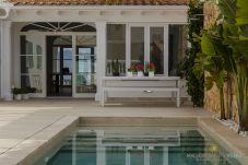 Private swimming pool with terrace and white Mediterranean façade at Villa Veles Dos in Mallorca.