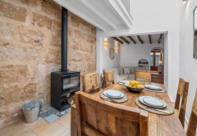 Living-dining room with fireplace, wooden table, and sofa in a rustic setting.