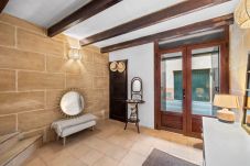 Hall d’entrée avec murs en pierre, poutres en bois et décoration chaleureuse avec miroir et banc tapissé